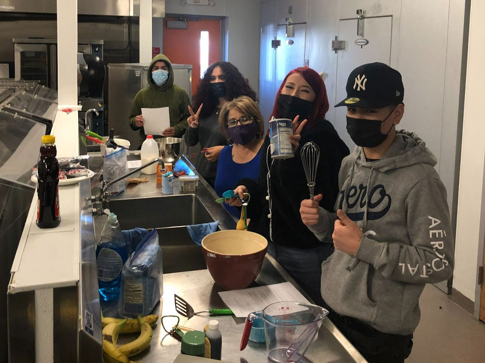Decorative photo of students and educators cooking in an industrial kitchen together