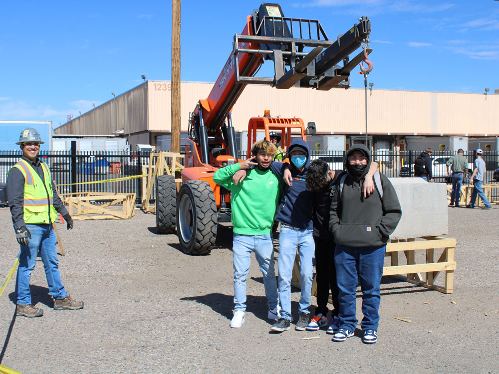 Decorative photo of students in front of heavy machinery in a work yard