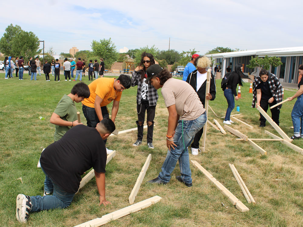 Decorative photo of students constructing a timber frame together outside.